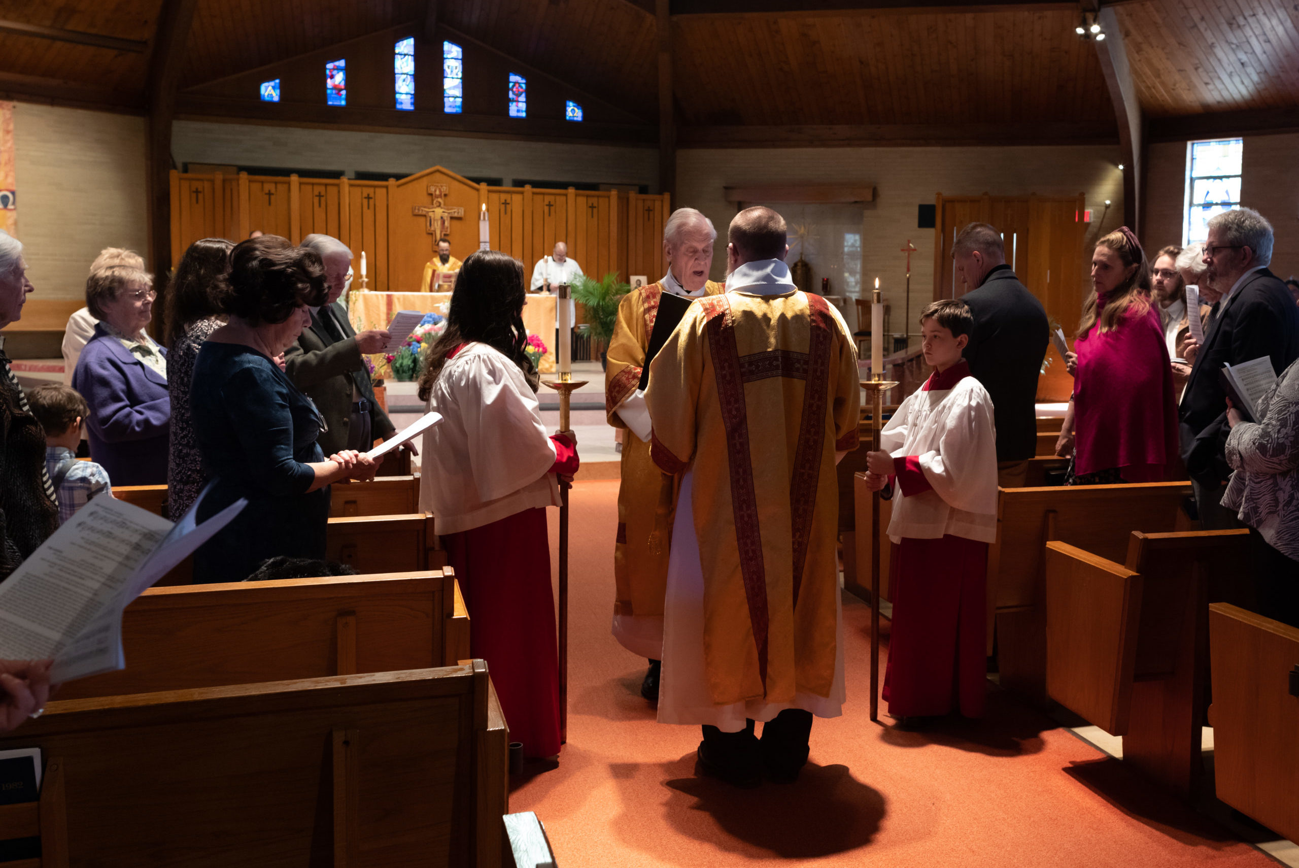 Father Malcom Reid reading the gospel in procession with acolytes
