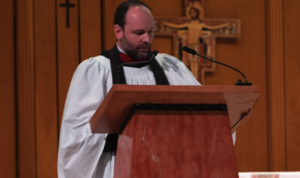 Father Brian Chase teaching at lectern